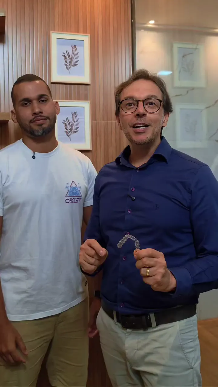 Paciente Marcos Vinícius ao lado do Dr. Valdemar segurando o alinhador