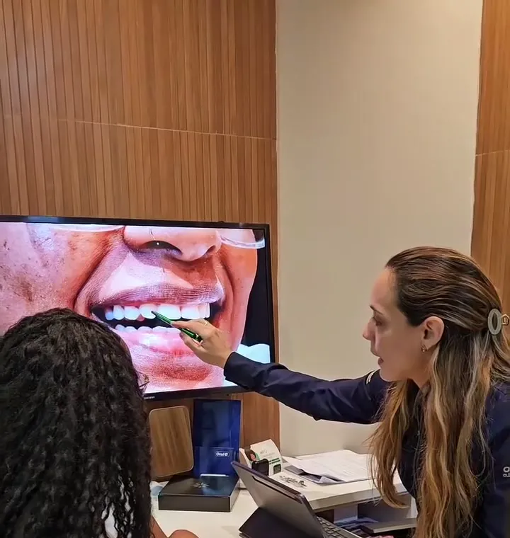 Dentista mostrando o sorriso da paciente na tela durante a consulta